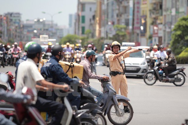 Những giọt mồ hôi lăn dài trên má, Trung uý Võ Điệp (Đội Cảnh sát Giao thông Số 3) cho biết: Các đồng nghiệp nam giới đứng bục phân làn mỗi ca 8 tiếng. Ảnh: Minh Sơn/Vietnam