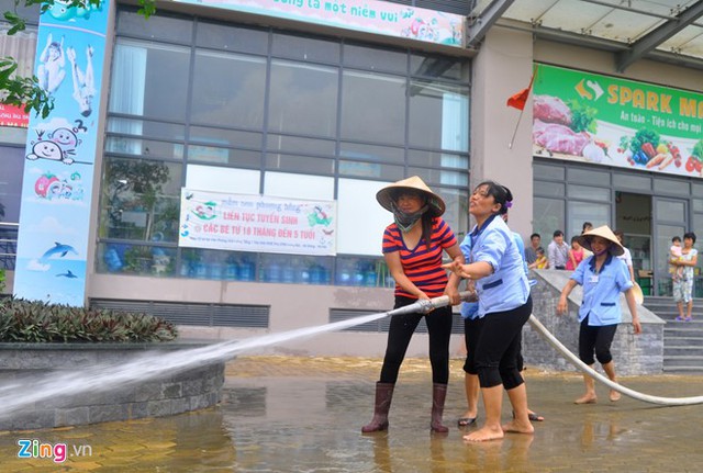 
Bên trong nhân viên vệ sinh khu chung cư dùng vòi nước rửa hành lang trước thềm tòa nhà.
