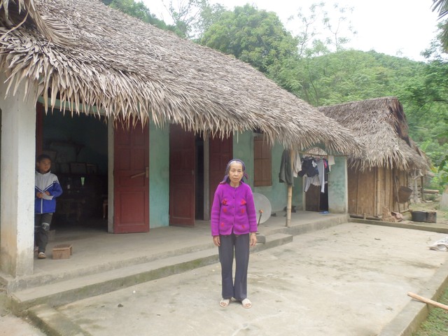 Bà Vi Thị Việt bên cạnh ngôi nhà xập xệ. Ảnh: N.Hưng