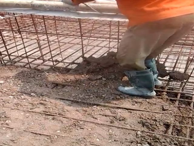 Công nhân dùng chân nhồi bê tông lẫn đất xuống phía dưới đế móng cột điện. (Ảnh từ clip).