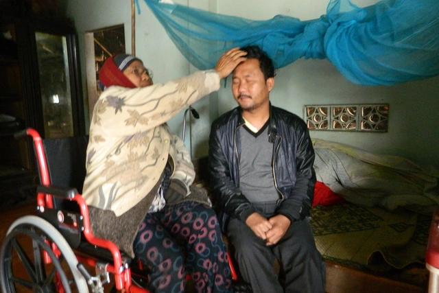 Bà Dương Thị Kỳ cố gắng dùng chút sức lực còn lại của mình để chăm sóc cho đứa con trai mù lòa. Ảnh: L.Chung