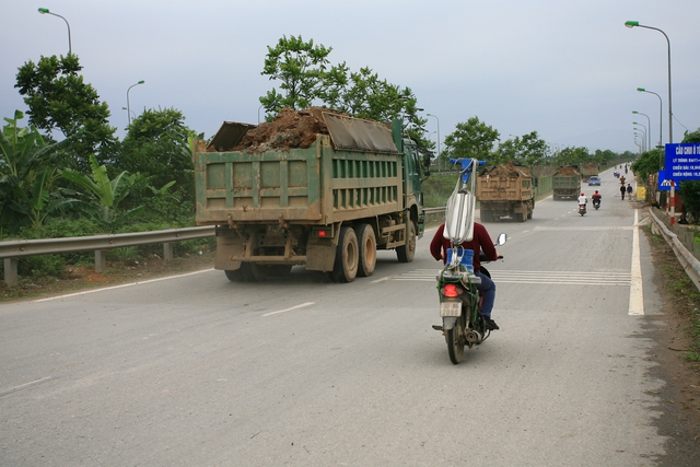 Cả đoàn xe tải chở đất vượt quá thành xe chạy rầm rầm trên Đại lộ Thăng Long.