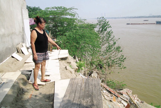 Bà Phạm Thị Bình chỉ cho phóng viên dấu tích ngôi nhà của mình bị sụt trôi. Ảnh: Ngọc Thi