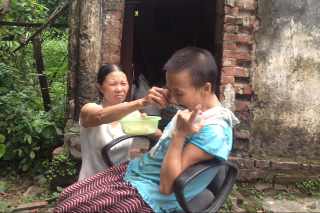 Bà Hoa hàng ngày bón cơm cho cô em chồng tật nguyền, ngô nghê ăn. Ảnh: T.G