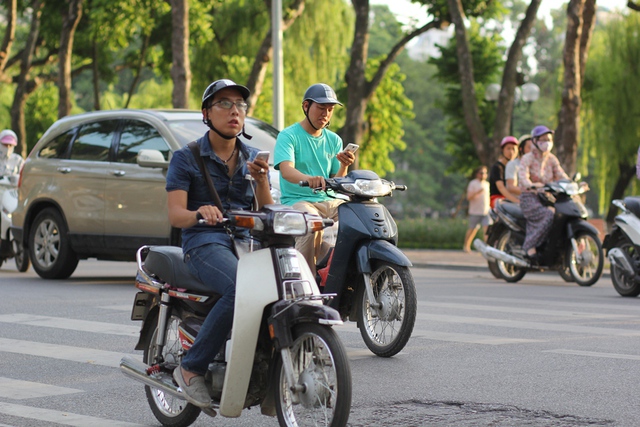 
Tuy nhiên, điều đáng lo ngại là không ít người đang điều khiển xe máy giữa phố đông đúc nhưng vẫn cầm smartphone và dán mắt vào màn hình.
