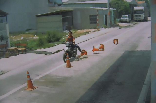 Người đàn ông đi xe máy không đội mũ bảo hiểm dùng chân đá văng dãy phân làn giao thông. Ảnh: Đức Hoàng