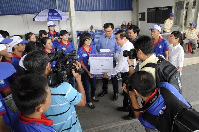 Ông Bùi Văn Huống - Phó Tổng giám đốc Công ty Cổ phần Tập đoàn Thiên Long (áo trắng) tặng quà cho các sinh viên tình nguyện tại bến xe Miền Tây.