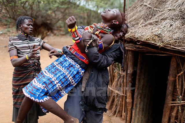 Một người đàn ông giữ cho cô bé không vùng vẫy khi cô cố chạy trốn. Ảnh: Siegfried Modola/Reuters