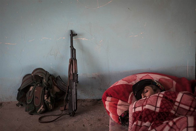 Shavin Bachouk vùi mình trong đống chăn tại một đồn bốt của quân đội bị bỏ hoang ở ngoại ô Raabia, Syria.