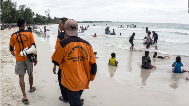 Các thành viên của Cơ quan quản lý thiên tai Indonesia đi bộ tại một bãi biển để tìm kiếm chiếc máy bay mất tích.
