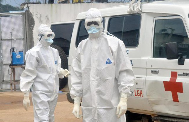 Hai nhân viên y tế mặc đồ bảo hộ đang chờ để mang thi thể của một người bị nghi đã chết vì Ebola hôm thứ Hai tại Monrovia, Liberia.
