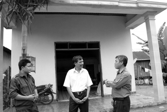 Ông ALăng Thưa (ở giữa) vui vẻ trước ngôi nhà mới xây cho biết bây giờ không sợ “con ma” nữa.	 Ảnh: Đ.H