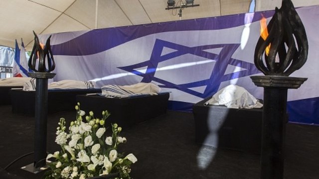 The bodies of four victims are placed in front of an Israeli national flag at a cemetery in Jerusalem