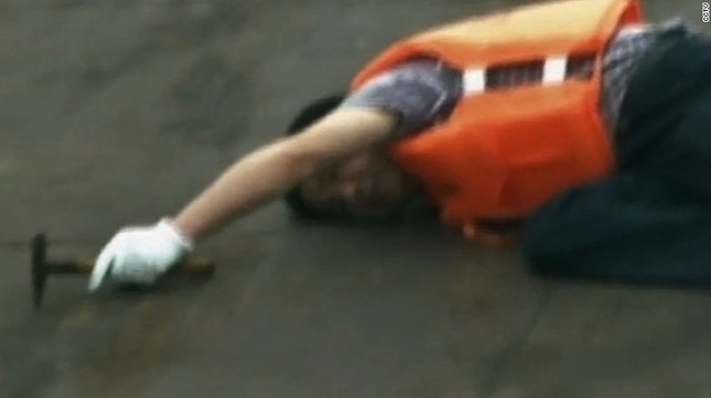 In this still frame from CCTV video, a rescue worker listens for voices inside the ship as he taps the hull of the capsized vessel.