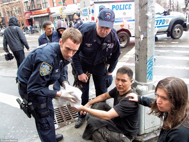 An NYPD officer tended to a sushi restaurant worker, who crouched on the ground with his back against a traffic light