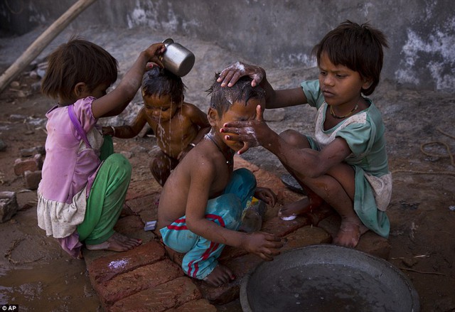 Two young girls bathe their siblings by a public tap on a hot summer day at Badshahpur, on the outskirts of New Delhi, India