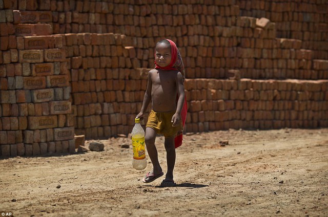 A young boy, the son of a worker, walks to a water pump to fill his bottle with drinking water in Ghasera, on the outskirts of New Delhi