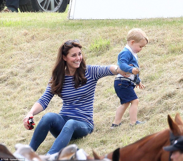 An amused Kate holds Georges toy car for him as he goes for an adventurous wander up the hill