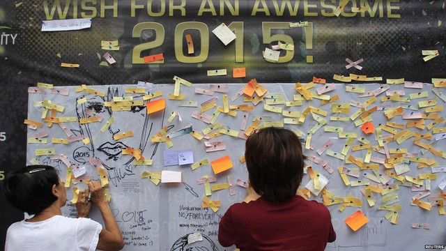 Onlookers write and post their New Year wishes on a wishing wall display at a mall in Quezon city, metro Manila 31 December 2014. 