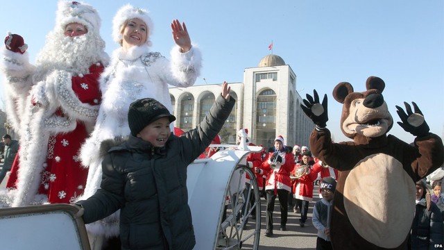 A man and a woman dressed as Father Frost (L) and his granddaughter (2-L) wave from a horse-drawn carriage as they take part in a New Year parade in Bishkek, Kyrgyzstan, 31 December 2014. 