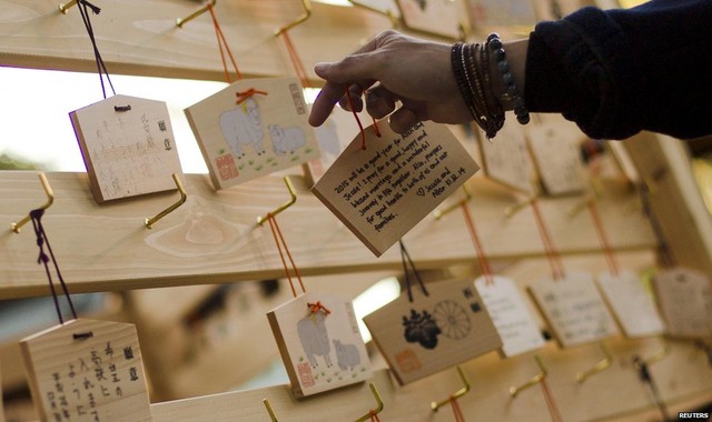 A man hangs a wooden plaque with peoples wishes or prayers on a hook during ceremonies bidding farewell to 2014, at the Meiji Shrine in Tokyo on 31 December 2014