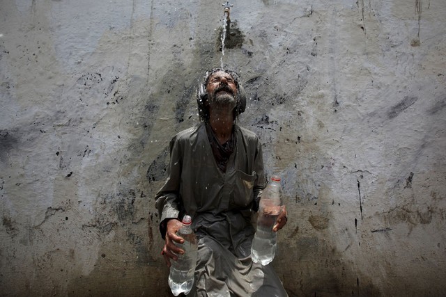 Đợt nắng nóng dữ dội đang hoành hành khắp miền nam Pakistan đã cướp đi sinh mạng của khoảng 1.000 người. Trong ảnh, một người đàn ông đang để vòi nước công cộng xả lên người cho mát, sau khi đã lấy đầy 2 chai nước giữa thời tiết nóng dữ dội ở Karachi, Pakistan