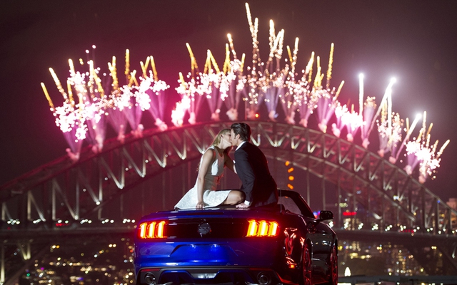 Sydney locals Demi Bryant and James Hundt celebrate the beginning of the New Year atop a high-rise overlooking the iconic Sydney New Years Eve fireworks display aside their next dream car, the all-new 2015 Ford Mustang.