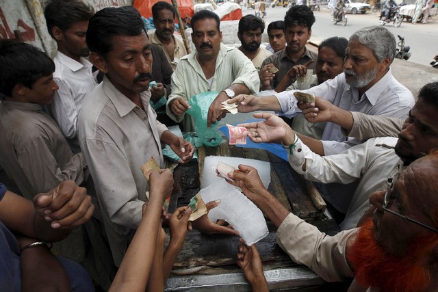 Nhiều người dân ở Karachi đã phải sống như “trong địa ngục” khi liên tiếp bị cắt điện và mất nước khiến họ gần như không thể chống chọi được với nắng nóng oi bức. Trong ảnh, nhiều người đang đưa tiền ra để mua đá lạnh trên đường từ một nhà cung cấp ở Karachi, Pakistan
