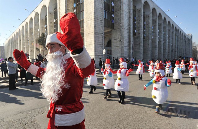 Tại Kyrgyzstan, đón chào năm mới cũng trở thành một sự kiện phổ biến ở quốc gia Trung Á này. Trong ảnh người đàn ông đi trước dẫn đầu những đứa trẻ trong trang phục người tuyết tại cuộc diễu hành chào đón năm mới 2015 ở thủ đô Bishkek của Kyrgyzstan.