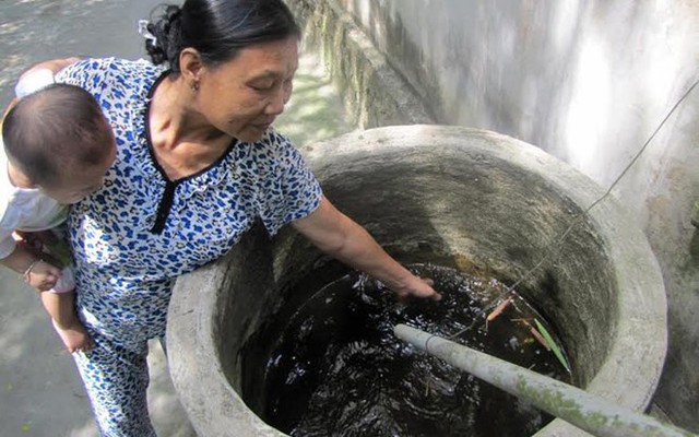 Bà Trần Thị Điểm, một người dân thôn Trung Trinh chỉ vào nguồn nước của gia đình vẫn dùng để sinh hoạt cho dù bị nhiễm thuốc sâu nặng.