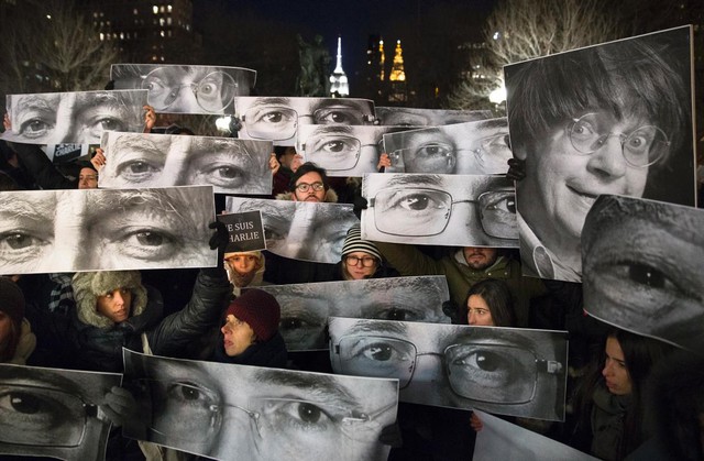 Mourners hold signs picturing the eyes of some of the victims of the terror attack on Charlie Hebdo magazine in Paris during a vigil Wednesday night in Manhattans Union Square.