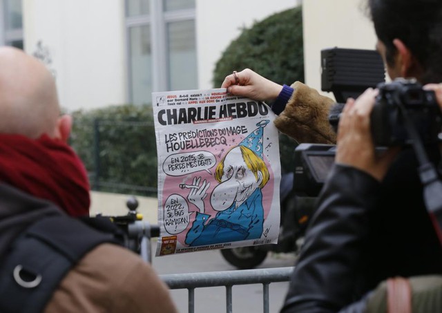 Một thành viên của giới truyền thông giơ hình ảnh trang nhất của Charlie Hebdo, trên đó có bức tranh biếm họa của tác giả người Pháp Michel Houellebecq, gần văn phòng tòa soạn của tuần báo châm biếm này.