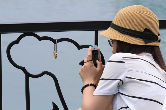 Một cô gái lưu lai hình ảnh khóa tình yêu sau khi đã khóa tình yêu lại trên cầu tàu...