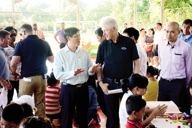 Cựu Tổng thống Bill Clinton cùng Thứ trưởng Bộ Y tế Nguyễn Thanh Long đến thăm Trung tâm Giáo dục, Lao động, Xã hội 02, ngày 18/7/2014. 	Ảnh: TL