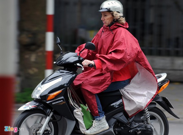 Tuy trời khá khô ráo và không mưa nhưng người phuj nữ nước ngoài vẫn khoác chiếc áo mưa bên ngoài khi đi xe máy để bảo vệ sức khỏe.