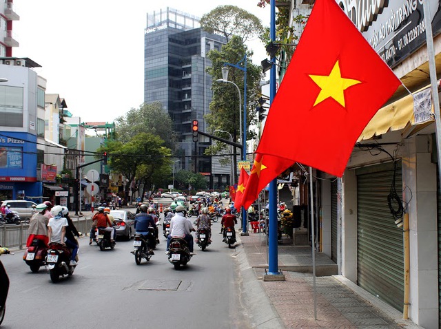 Cờ đỏ sao vàng rực rỡ trên từng con phố và bay phấp phới trong nắng êm dịu của Sài Gòn sáng mùng 1 Tết Ất Mùi. (Ảnh chụp trên đường Đinh Tiên Hoàng, Q.1)