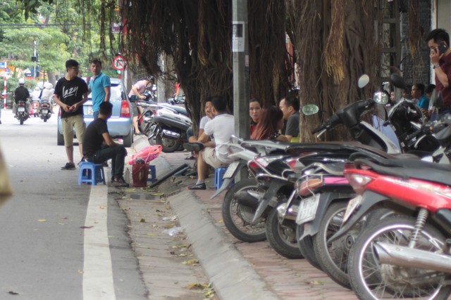 Xe máy, quán cà phê tràn ra vỉa hè để người đi bộ phải đi dưới lòng đường ở phố Nguyễn Du. 	Ảnh: H.P