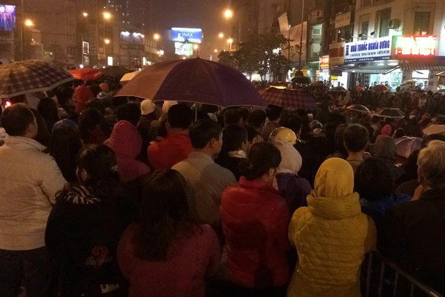 Người dân đội mưa, tràn ra đường tại lễ cầu an ở chùa Phúc Khánh tối 4/3. 	Ảnh: Hạnh Nguyên