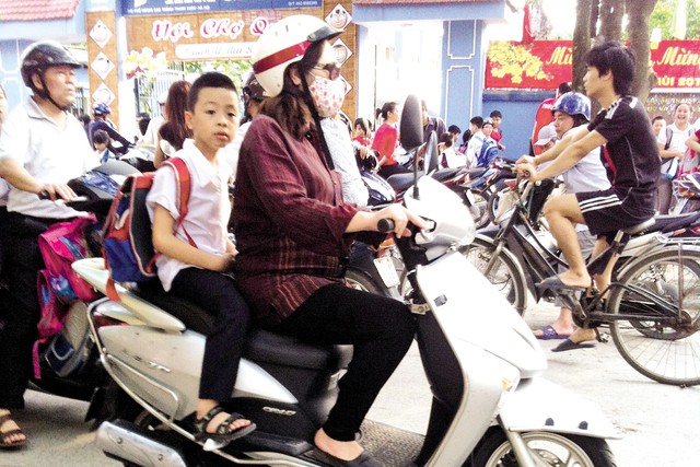 Theo ghi nhận của PV Báo GĐ&XH, tính đến chiều 31/3, tại nhiều trường tiểu học ở Hà Nội phần lớn phụ huynh vẫn chưa đội mũ bảo hiểm cho con khi đưa đón. 	Ảnh: Q.Anh