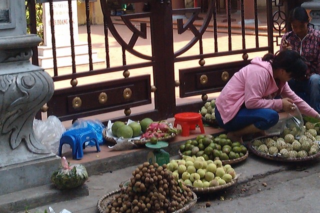 Người bán hàng này thản nhiên bày bán các loại trái cây ngay trước cổng đình Hoàng Cầu. 	Ảnh: N.Mai