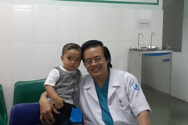 Bác sỹ Nguyễn Văn Đẩu và một bệnh nhi đã được ông phẫu thuật. 	 ảnh: T.G