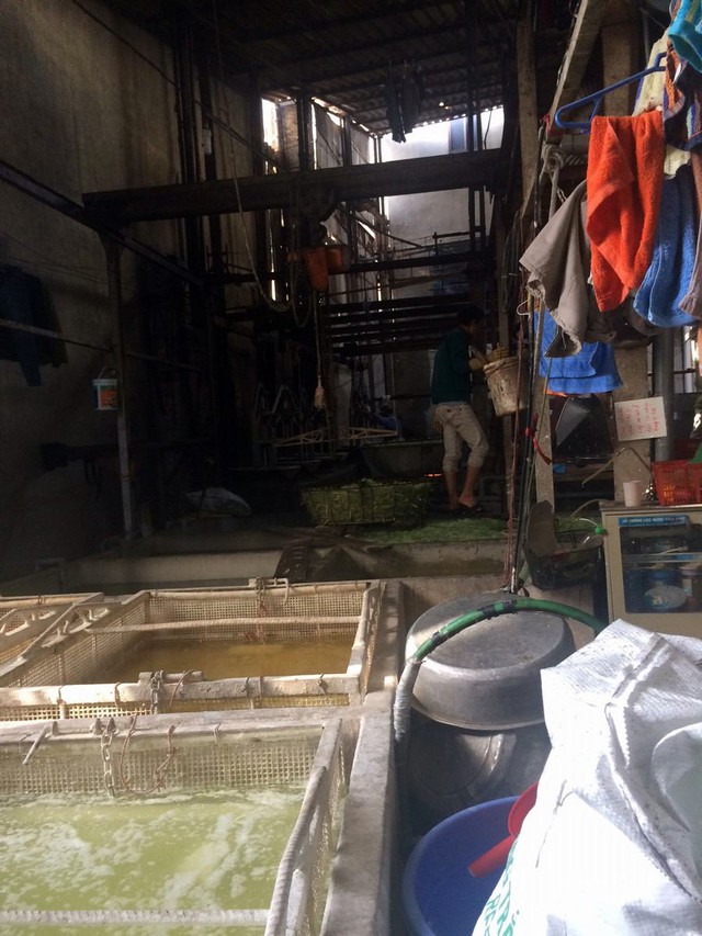 Bên trong một cơ sở sản xuất, đập vào mắt là những bể nước đóng váng, quần áo, xô chậu và ba bì ngổn ngang (ảnh LĐ)