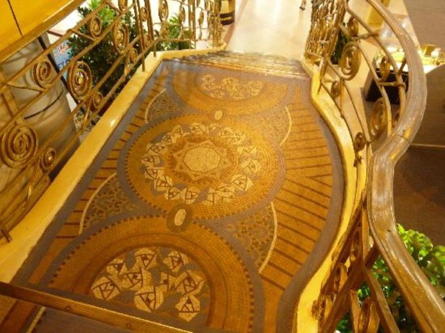 Cầu thang cò lan can bằng đồng, trang trí gạch mosaic tại sảnh chính Thương xá Tax