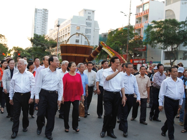 Thủ tướng Nguyễn Tấn Dũng cùng phu nhân (áo đỏ) và lãnh đạo Bộ VH-TT-DL, lãnh đạo TP HCM vui vẻ dạo bước trên đường hoa Hàm Nghi. Thủ tướng tươi cười vẫy tay chào mọi người cùng tham quan đường sách vào dịp Xuân về