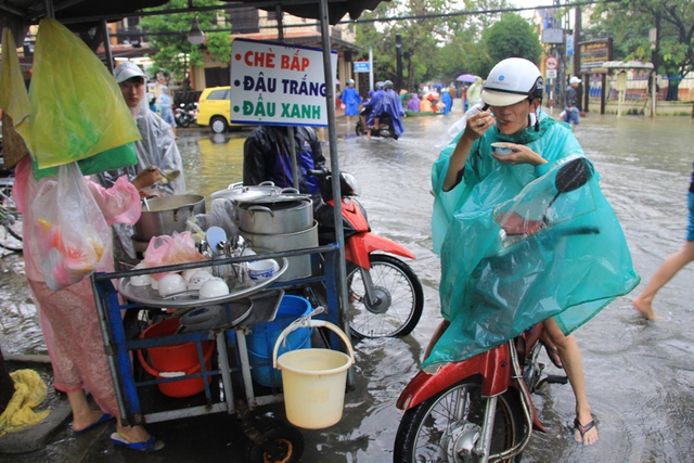 Ngồi trên xe, đứng giữa nước lũ ngập phố ăn vội bát chè nóng trước khi về nhà...