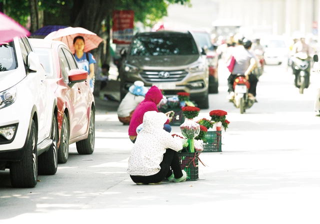 Ngồi bán hoa dưới lòng đường Nguyễn Trãi có mật độ giao thông rất đông.