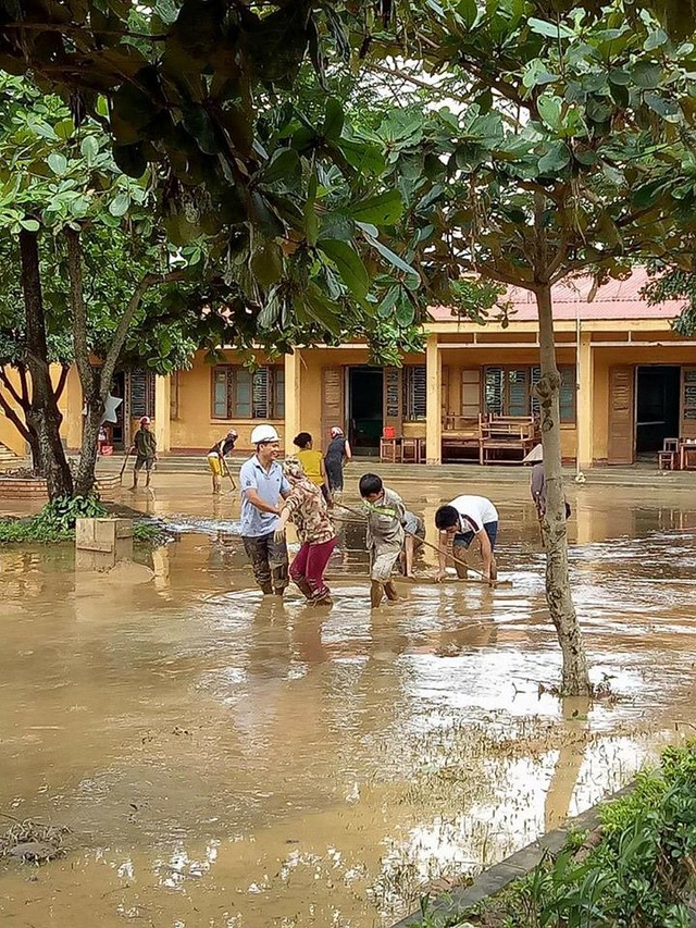 Các thầy cô giáo đang dọn bùn đất sau lũ.