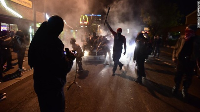 
Những người biểu tình ném các vật dụng vào cảnh sát, đập phá các cửa hàng và các xe hơi bên đường.
