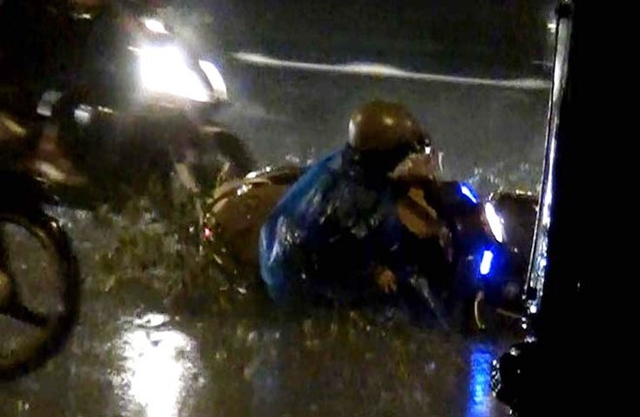 Người đi xe m&aacute;y bị sụp hố ng&atilde; xuống đường. Ảnh cắt từ clip.