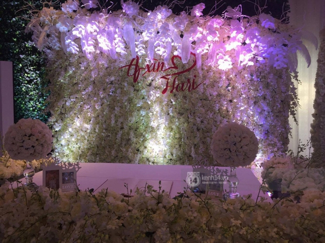 
Phông nền chụp ảnh cưới được trang trí thành bước tường hoa hồng trắng, nổi bật là chữ A Xìn và Hari màu đỏ.
